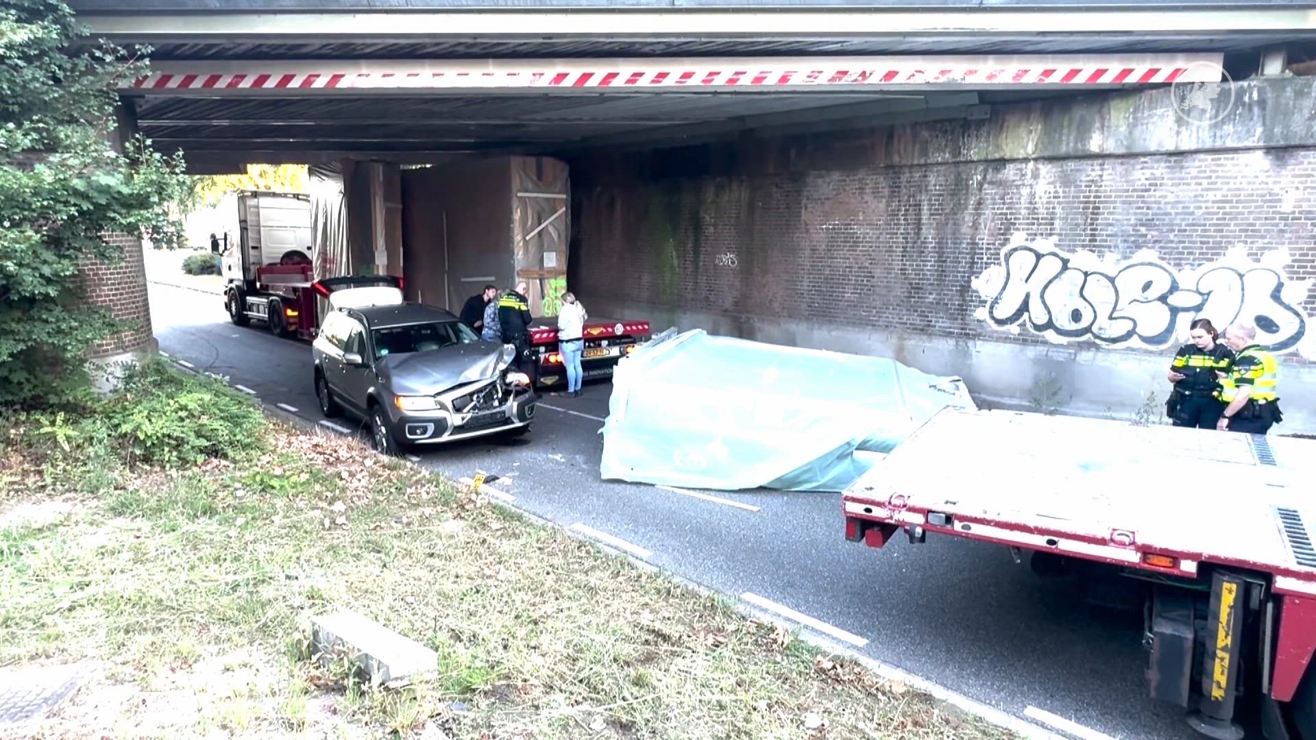 Auto beschadigd nadat vrachtwagen lading verliest bij viaduct.